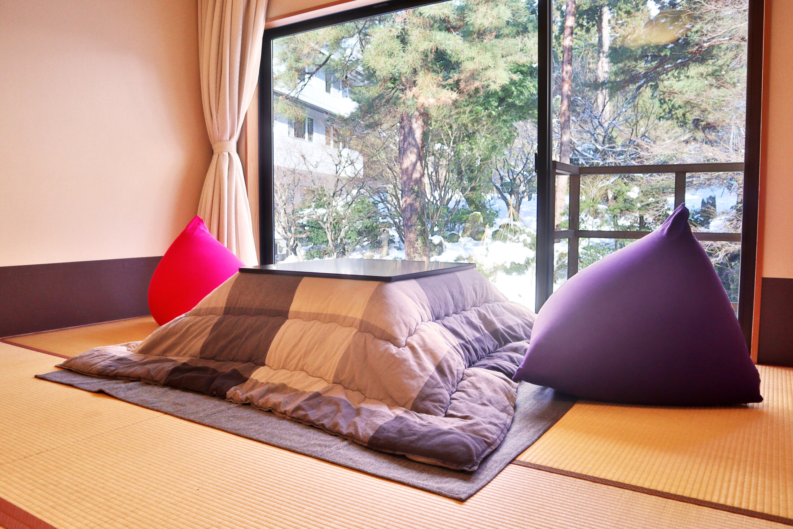 【滝見亭和室】壁一面の窓から望む滝。冬はこたつで温まるひととき